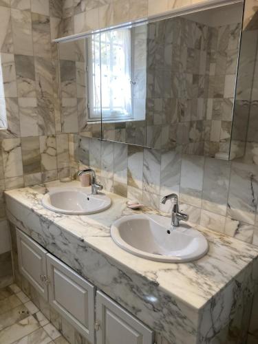 une salle de bain en marbre avec deux lavabos et un miroir dans l'établissement Villa Marguerite, à Lorgues