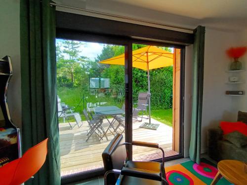 a sliding glass door leading to a deck with an umbrella at OUT a TIME in Angoville-sur-Ay