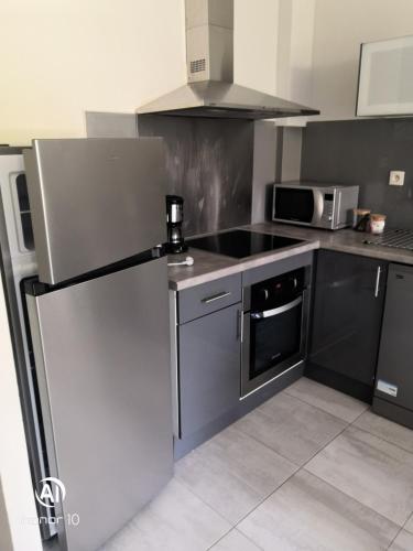 une cuisine avec un réfrigérateur en acier inoxydable et un micro-ondes dans l'établissement le central 300 metres de la plage, à Cassis