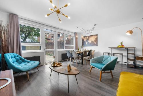 a living room with blue chairs and a table at Spacious 3 bedroom Whitechapel Apartment with Garden by Gold Stays in London