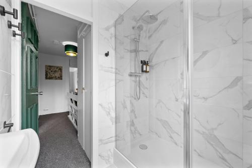 a bathroom with a shower with a glass door at Spacious 3 bedroom Whitechapel Apartment with Garden by Gold Stays in London
