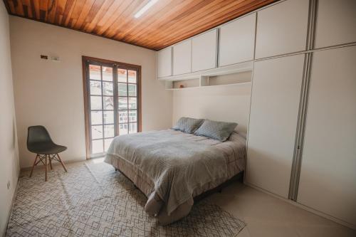 a bedroom with a bed and a chair in it at Portal Flores Suítes in Campos do Jordão