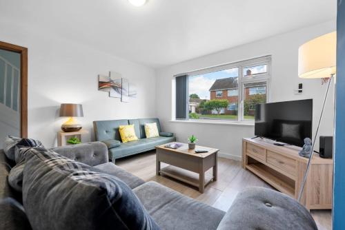 a living room with a couch and a tv at Legacy House - Secured Parking on Site in Tollbar End