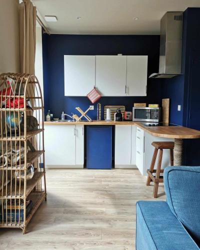 une cuisine avec des armoires blanches et un mur bleu dans l'établissement Bulle marine paisible proche de la gare et du port, à Brest