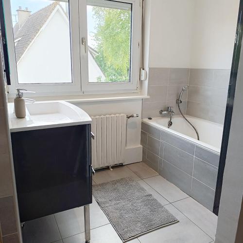 La salle de bains est pourvue d'un lavabo, d'une baignoire et d'une fenêtre. dans l'établissement La maison d'à côté, à Montreuil-sur-Mer