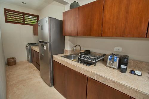 a kitchen with a sink and a stainless steel refrigerator at Villas Caracol in Holbox Island