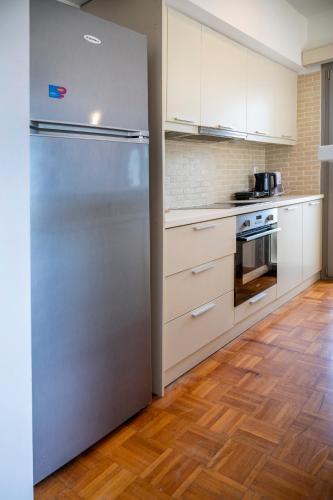 a stainless steel refrigerator in a kitchen with wooden floors at City Calm House in Platánion