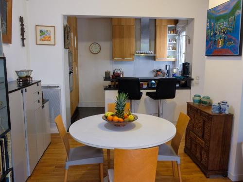 une cuisine avec une table avec un bol de fruits dessus dans l'établissement Maison avec jardin à deux pas de Paris, à Vanves