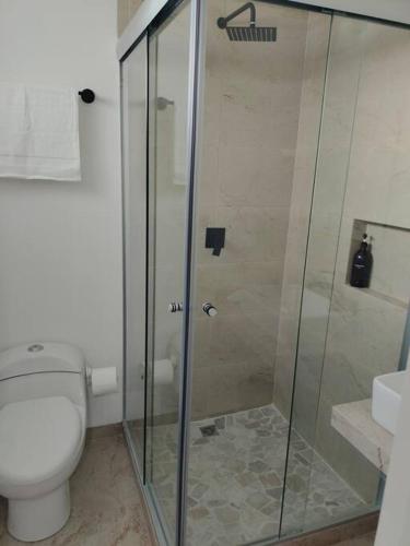 a bathroom with a toilet and a glass shower at Cerca de Salones de Fiesta, con Alberca, AC e Internet in Xochitepec