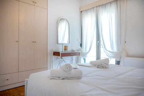 a white bedroom with a bed with two towels at City Calm House in Platánion
