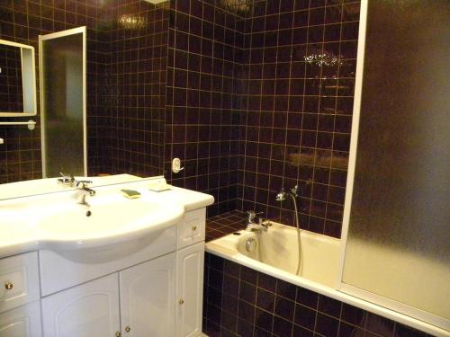 La salle de bains est pourvue de carrelage noir, d'un lavabo et d'une baignoire. dans l'établissement T2, centre village, belle terrasse proche plages, à Cassis
