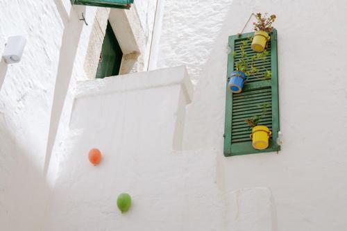 a white building with a window with two pots on it at Dimora Lavinia Casa vacanze Centro storico Ostuni in Ostuni