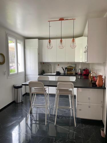 une cuisine avec des placards blancs et deux tabourets de bar dans l'établissement Charmante maison avec jardin aux portes de Paris, à Vitry-sur-Seine