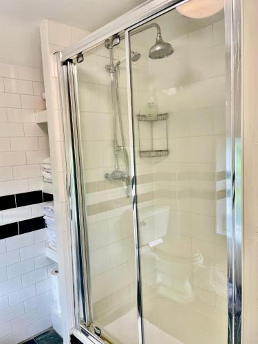 a shower with a glass door in a bathroom at Tythe Barn Cottage in Glastonbury