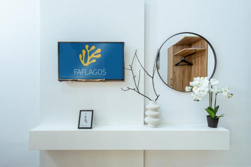 a sign on a mantle with a mirror and flowers at Faflagos Apartments in Psari Forada