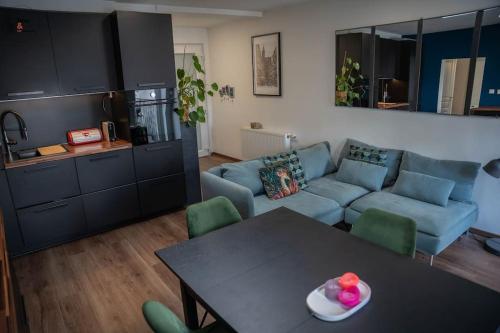 un salon avec un canapé bleu et une table dans l'établissement Le Roble - 5 min du centre de Strasbourg, à Strasbourg