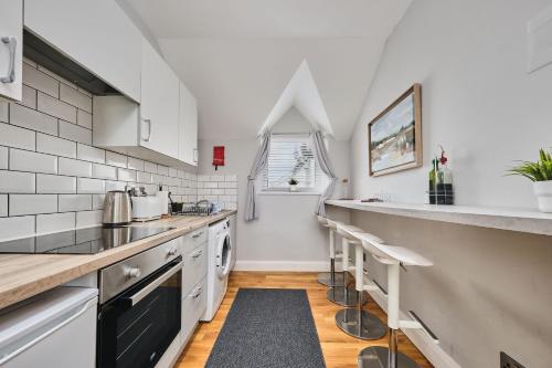 eine Küche mit weißen Geräten und einer Theke mit Hockern in der Unterkunft Dunluce Park 5 - Portrush by the Sea in Portrush