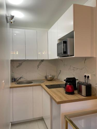 une cuisine avec des armoires blanches et un comptoir dans l'établissement Le Spot, à Paris