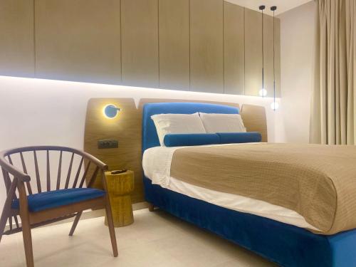 a bedroom with a blue bed and a chair at Tramonto Maisonettes & Suites in Parga