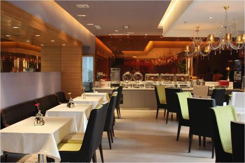 a restaurant with white tables and chairs and a kitchen at Jinjiang Inn Anyang Insititute of Technology in Anyang
