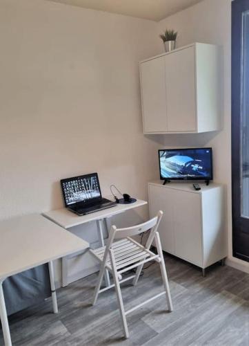 Cette chambre dispose d'un bureau, d'un ordinateur portable et d'une télévision. dans l'établissement Appartement plein sud avec terrasse, à Huez