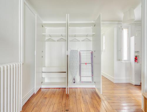 Cette chambre est dotée de murs blancs et de parquet. dans l'établissement Eiffel tower 10 minutes 1BR Renovated, à Paris