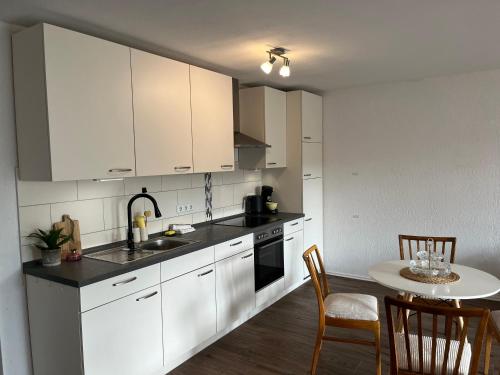 a kitchen with white cabinets and a table with chairs at Apartment Kastanienblick in Tettnang