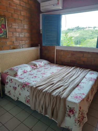 a bed in a room with a window at Casa Cantinho da Paz, seu lazer completo, churrasqueira, piscina e muita tranquilidade in Gravatá