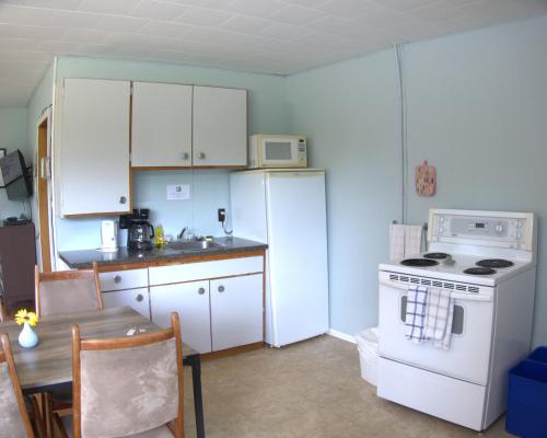 a kitchen with a white refrigerator and a table at Port loring Northland Motel in Port Loring