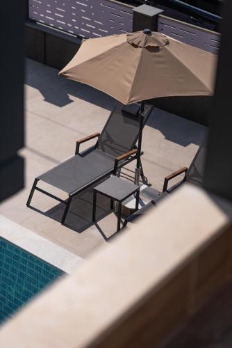 a chair and an umbrella next to a swimming pool at Horeizons Modern Living in Nea Vrasna