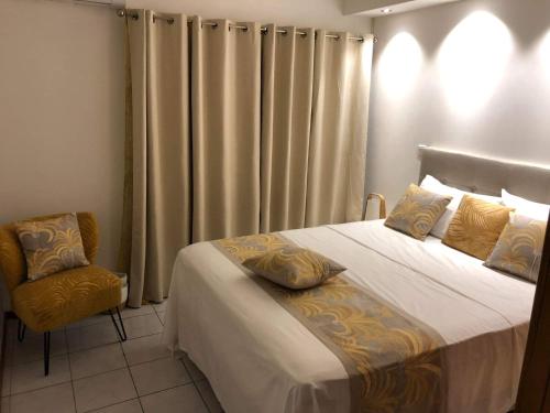 a bedroom with a bed and a chair and curtains at Poerava Tahiti in Papeete