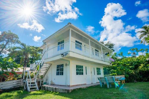 a white house with two blue chairs in the yard at Posada Mango Tree in Providencia