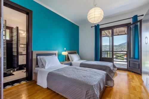 two beds in a room with blue walls at Alexandra Pool Villa - Comfort & Views Near Town in Skopelos Town