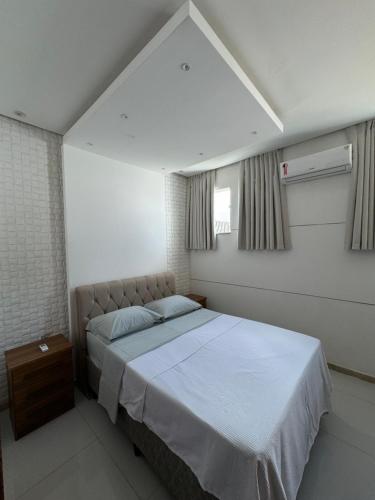 a bedroom with a white bed and a window at Duplex - Villa dos Diamantes in Porto Seguro