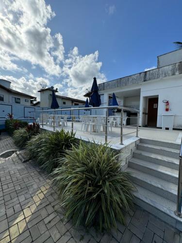 a patio with chairs and umbrellas on a building at Duplex - Villa dos Diamantes in Porto Seguro