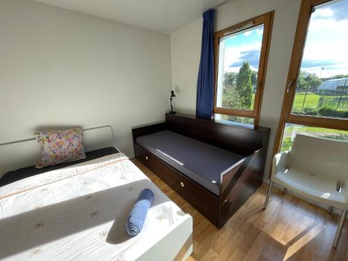 een slaapkamer met twee bedden en een stoel en een raam bij Studio lumineux 10 min à La Défense 2 in Rueil-Malmaison