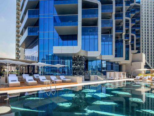 un hotel con piscina con sillas y un edificio en Hyde Hotel Dubai en Dubái