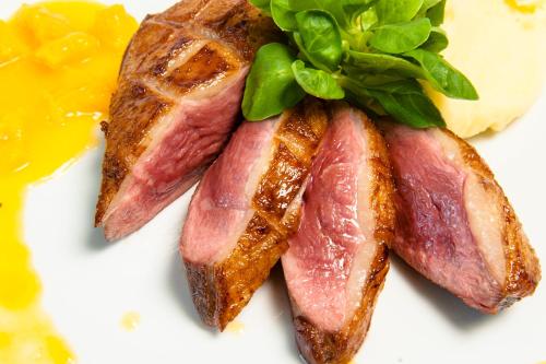a plate of food with bacon and greens on it at Hotel Parc Sibiu in Sibiu