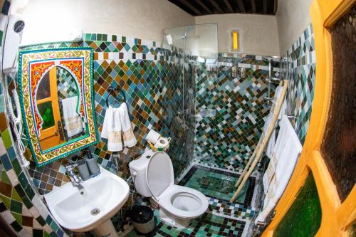 a tiled bathroom with a toilet and a sink at Riad Taj Fes in Fès