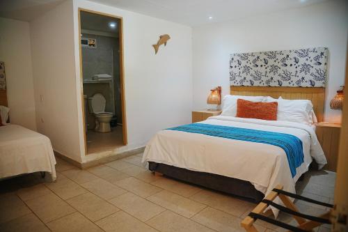 a bedroom with a bed and a bathroom with a toilet at Hotel Isla Real in Tierra Bomba