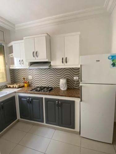 a kitchen with white cabinets and a white refrigerator at Duplex El mansoura A2 in Kelibia