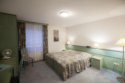 um quarto de hotel com uma cama e uma cadeira em Sobe Krona em Radovljica