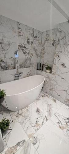 a bathroom with a white tub and marble walls at Bergen Sunrise Terrace Apartment in Bergen