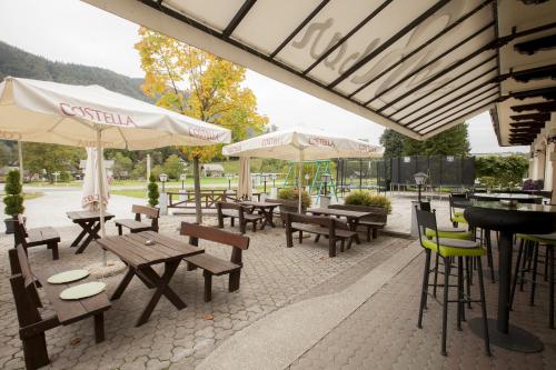 un patio con mesas de madera, sillas y sombrillas en Sobe Krona en Radovljica