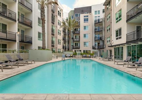 a large swimming pool with chairs and buildings at Stylish 1 Bedroom Apartment in LA with Free Parking - 10 Minutes away from Ceders Sinai in Los Angeles