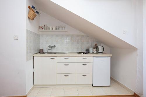 a kitchen with white cabinets and a sink under a staircase at Apartments by the sea Tisno, Murter - 815 in Tisno
