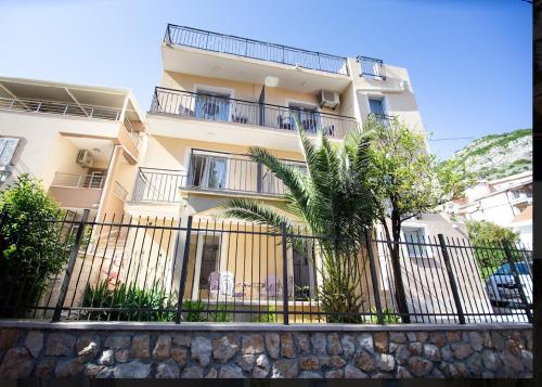 a building with a fence and palm trees in front of it at Soheds in Budva