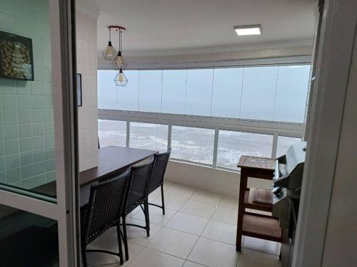 a kitchen with a table and chairs and a large window at Apto frente mar maravilhoso centro mongaguá in Mongaguá