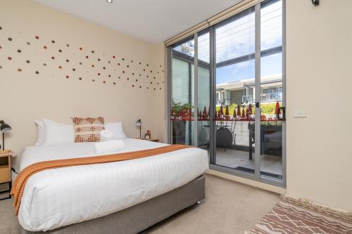 キャンベラにあるModern Two-Story City Pad With Pool, Gym & Saunaのベッドと大きな窓のある寝室