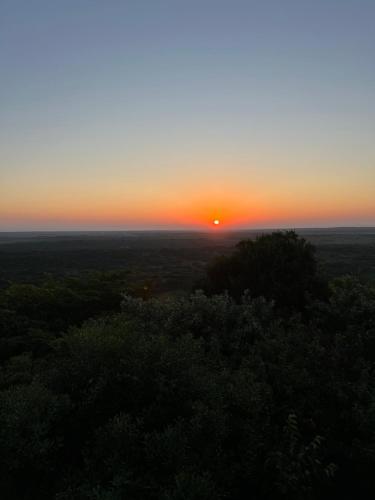 a sunset from the top of a hill with trees at Bruma Homes in Ponta do Ouro